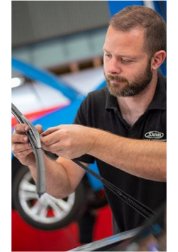 Automotive technician inspecting and measuring a vehicle wheel component during professional car maintenance